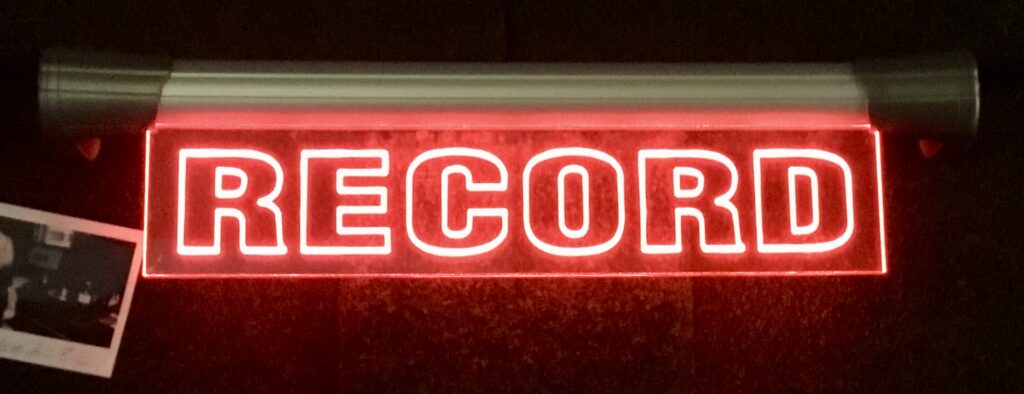 A red neon sign saying RECORD showing that a recording is going on